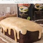 Chocolate Baileys banana bread with white chocolate Baileys ganache dripping down the sides, with Baileys Irish Cream bottles behind it.