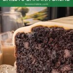 Slice of chocolate Baileys banana bread with white chocolate Baileys ganache and a Baileys bottle behind it.