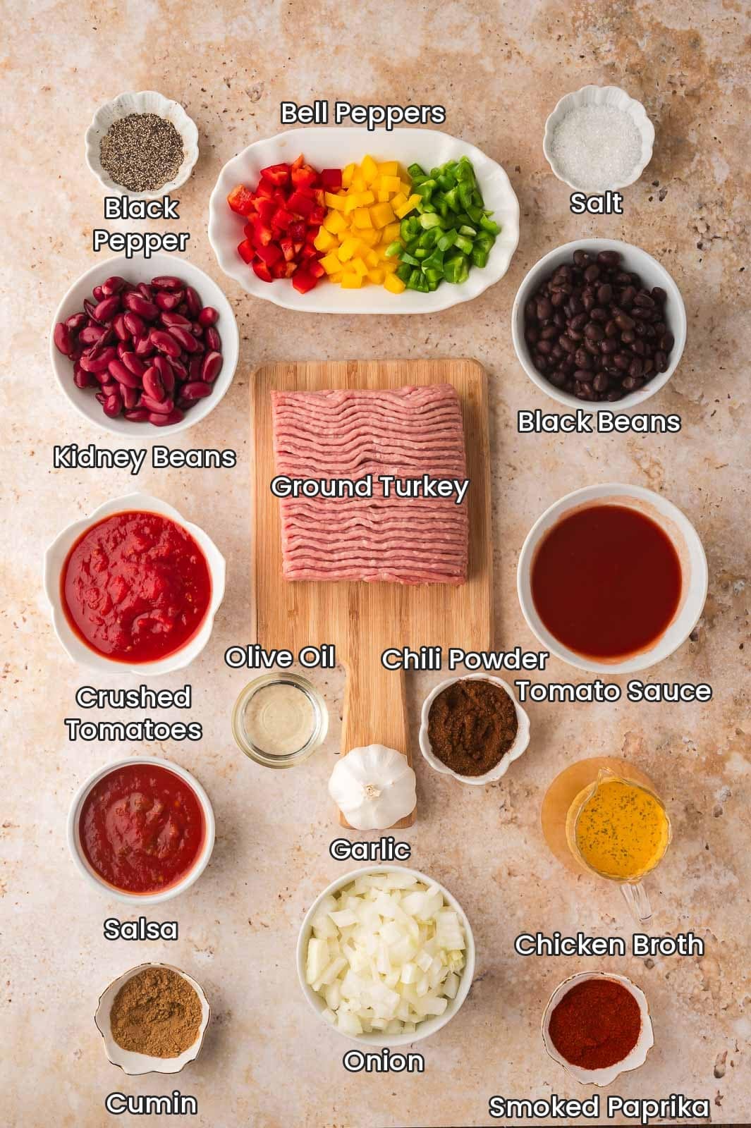 Labeled ingredients for slow cooker turkey chili including ground turkey, bell peppers, onion, garlic, black beans, kidney beans, crushed tomatoes, tomato sauce, salsa, chicken broth, olive oil and spices by Tessie's Table.