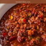 Close up of slow cooker turkey chili with kidney beans, black beans and bell peppers in a white crockpot.